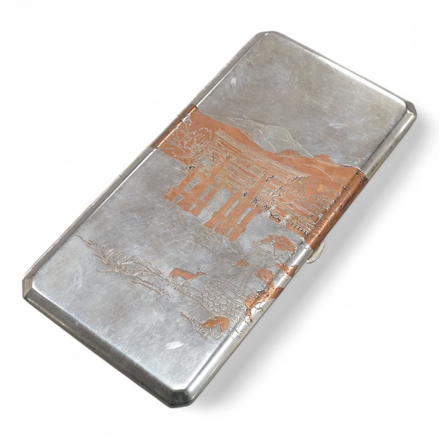 An early to mid 20th century Japanese mixed metal cigarette case, with Temple scene by the water with deer, engraved 'sterling' on the interior, 15.9cm, gross weight 5.8oz.